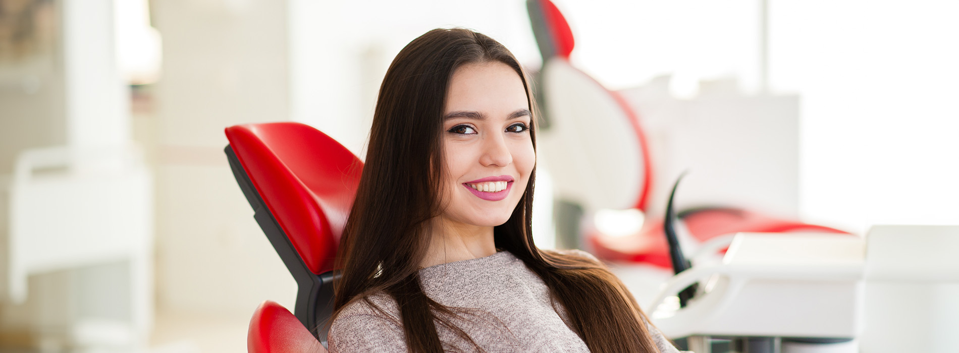 A woman in a modern office setting, smiling and posing for the camera.