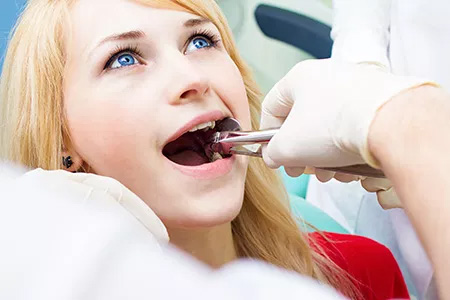 A woman receiving dental care, with a dental professional using tools to examine her teeth.