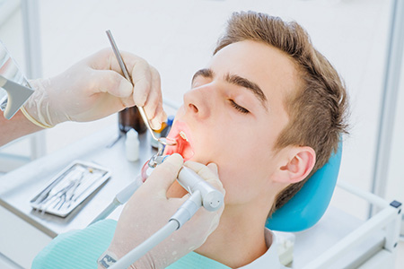 A dental professional performing a dental procedure on a patient in a clinical setting.