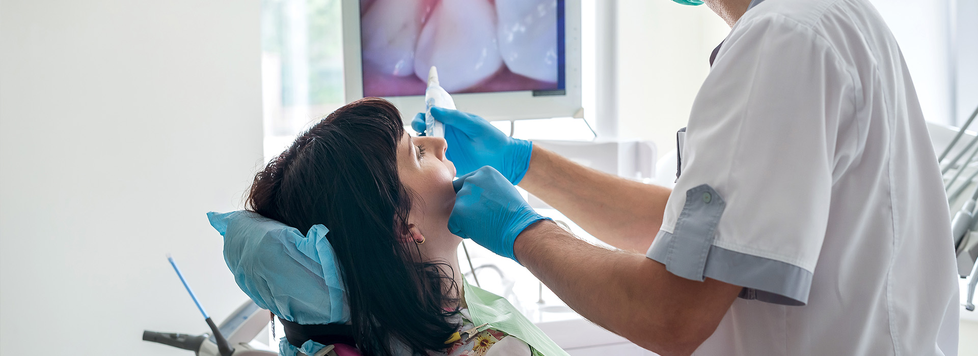 A woman receiving dental care in a professional setting, with a dentist performing the procedure.